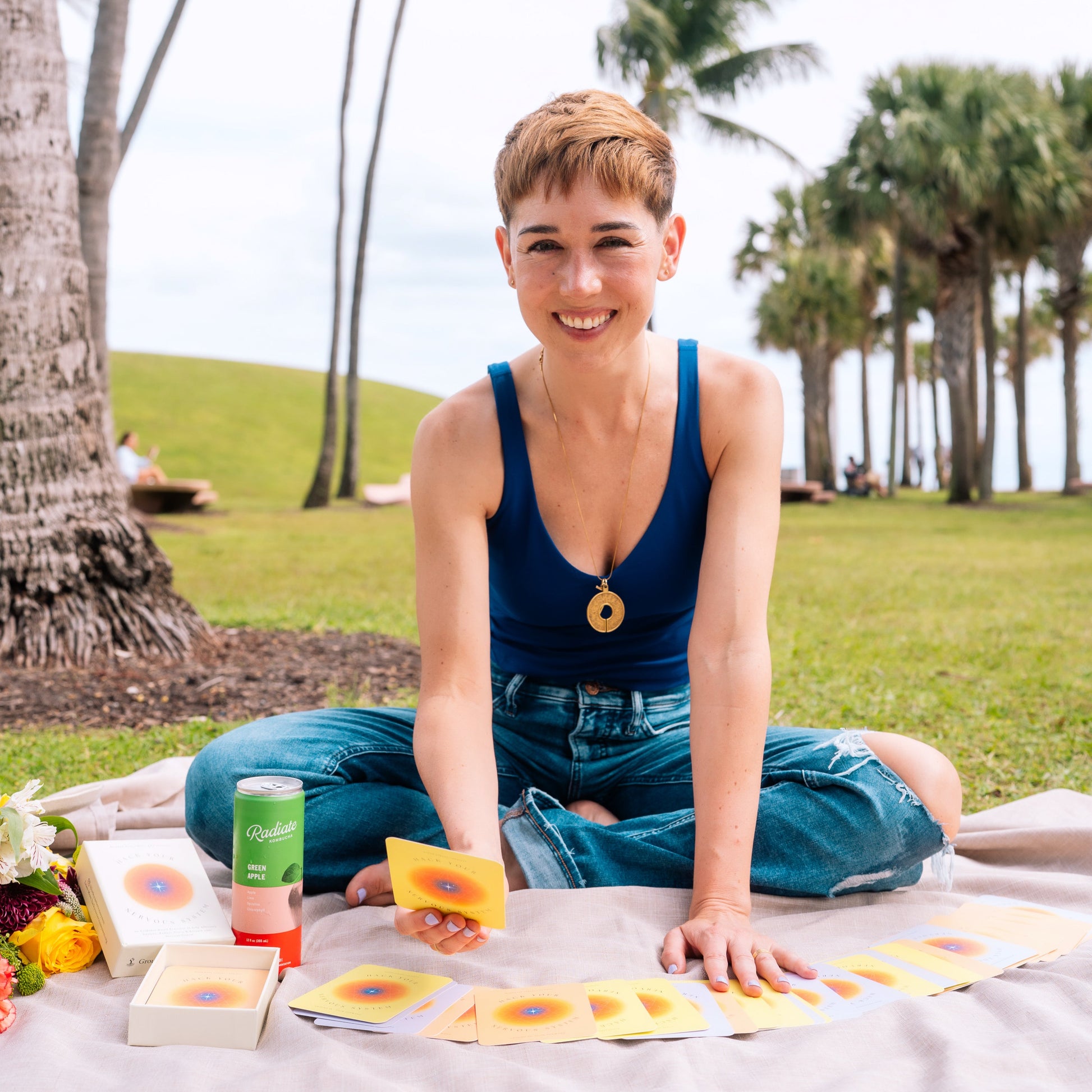 Woman sitting on a blanket outdoors with palm trees in the background