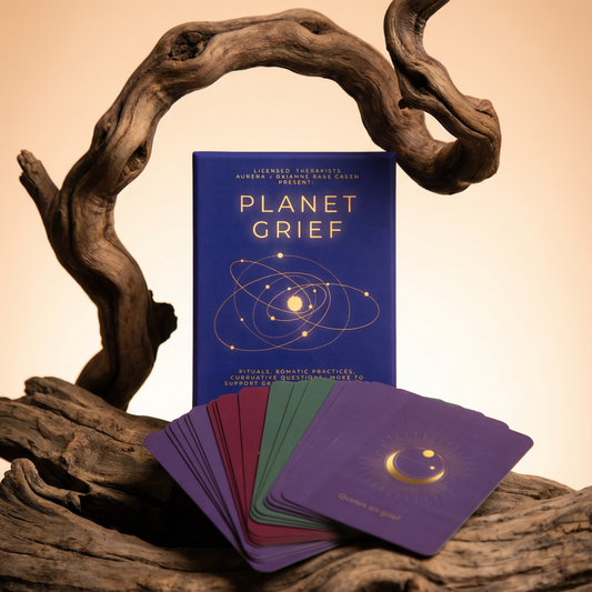 Book titled 'Planet Grief' with cards on a wooden surface